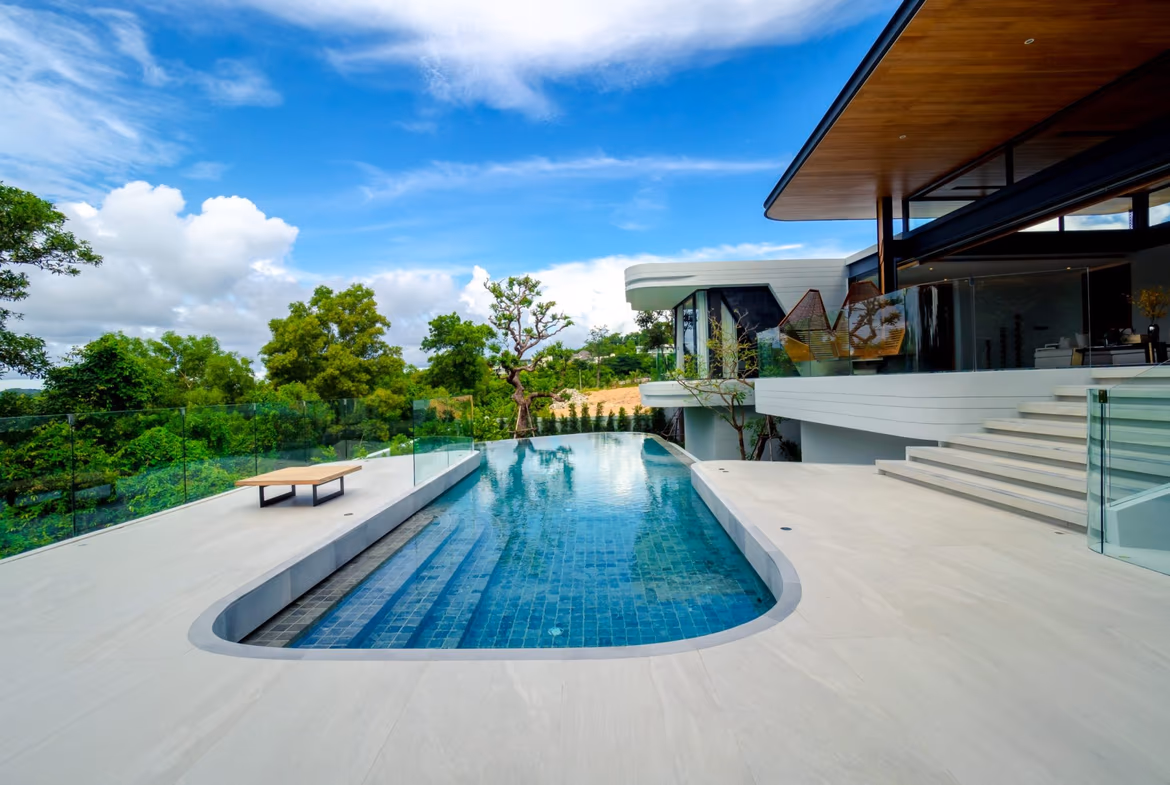 A modern living room with large glass doors opening to a swimming pool and outdoor seating area.