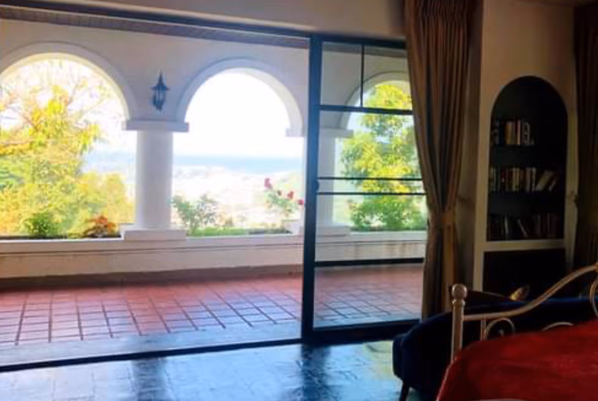 An expansive exterior view of a multi-story villa with several balconies, overlooking a large body of water.