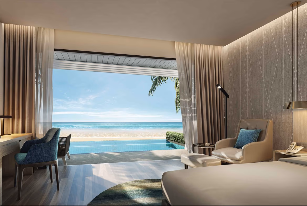 A spacious living room featuring modern furniture and large glass doors that open to a balcony with ocean views.