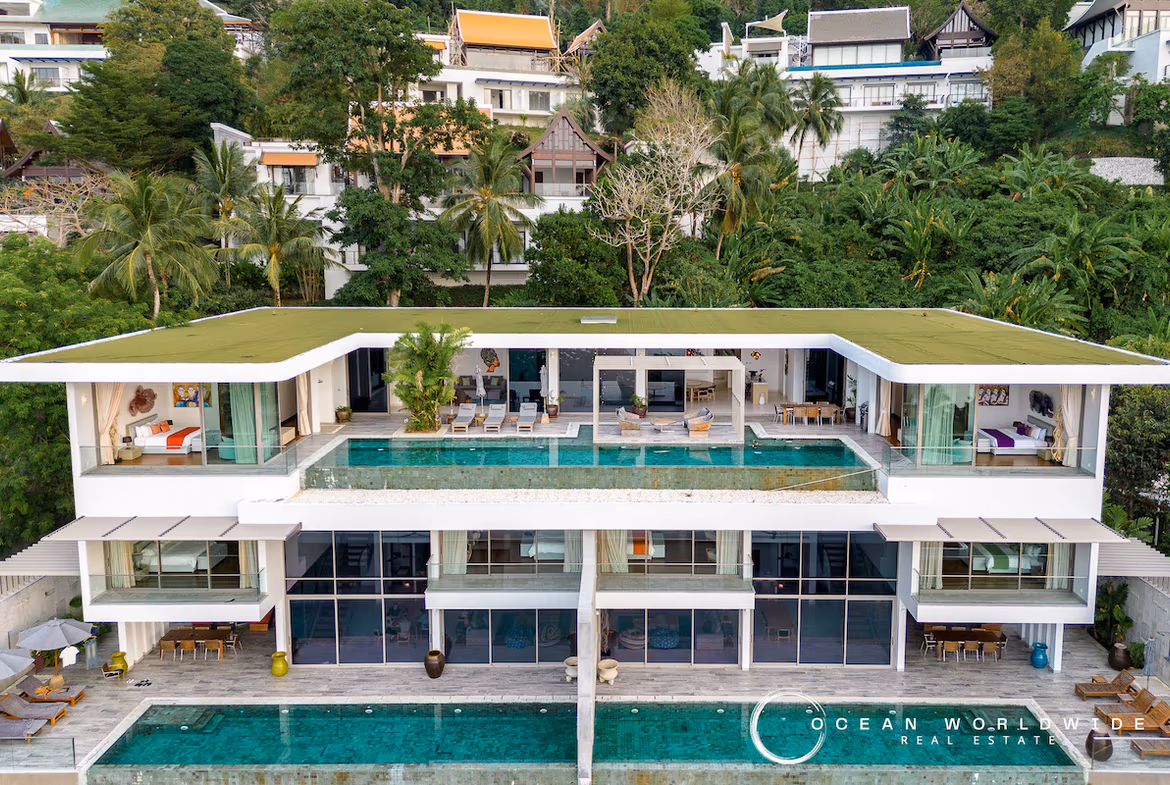 A modern, upscale kitchen with a large island and seating, featuring sleek appliances and ample cabinet space, with a view of the sea through large windows.