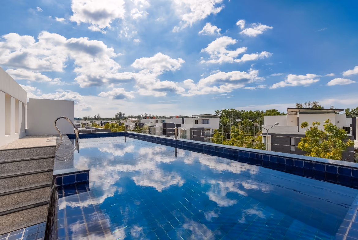 A spacious living area with modern furnishings and large windows overlooks a tropical garden and swimming pool.