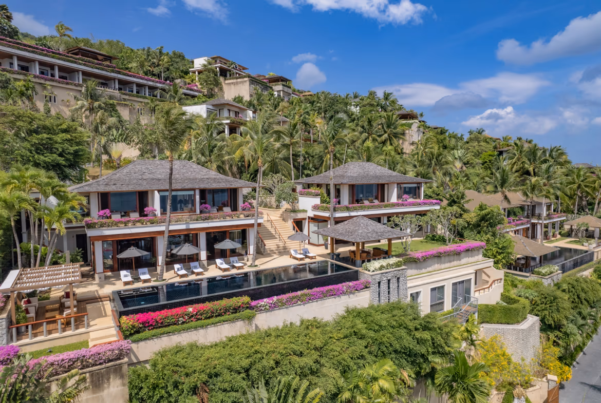 An infinity pool overlooks a serene ocean and distant mountains under a clear sky.