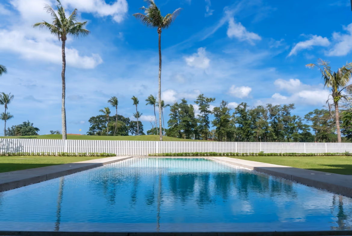 A spacious living room with modern furnishings and large windows overlooks a tropical garden.