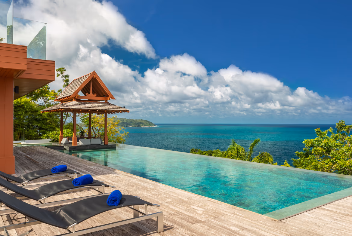 A stone patio offers an elevated view of the sea and distant hills.