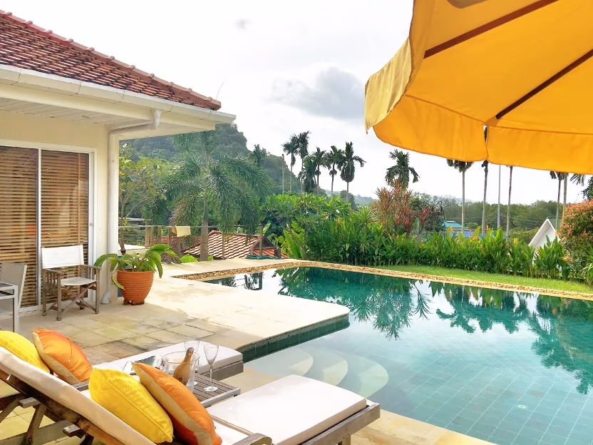 A spacious, modern living room with large windows overlooking a tropical landscape.