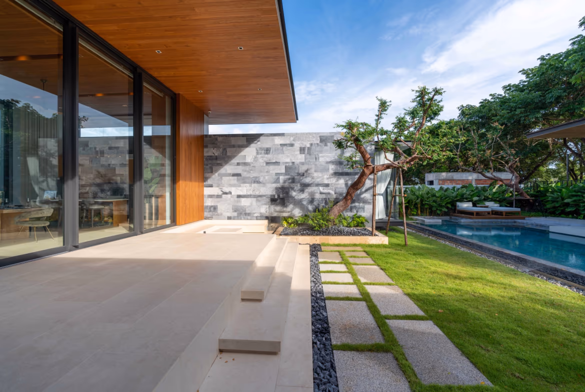 This photo shows a modern infinity pool overlooking a lake and distant buildings under a clear sky.
