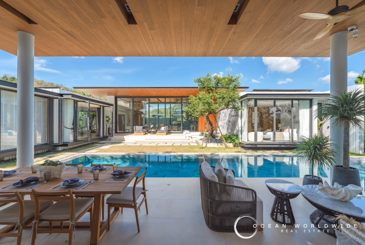 A four-bedroom villa in Koh Kaew features a private pool and a modern architectural style. The exterior shot shows the villa from a distance, highlighting its facade and surrounding landscape.