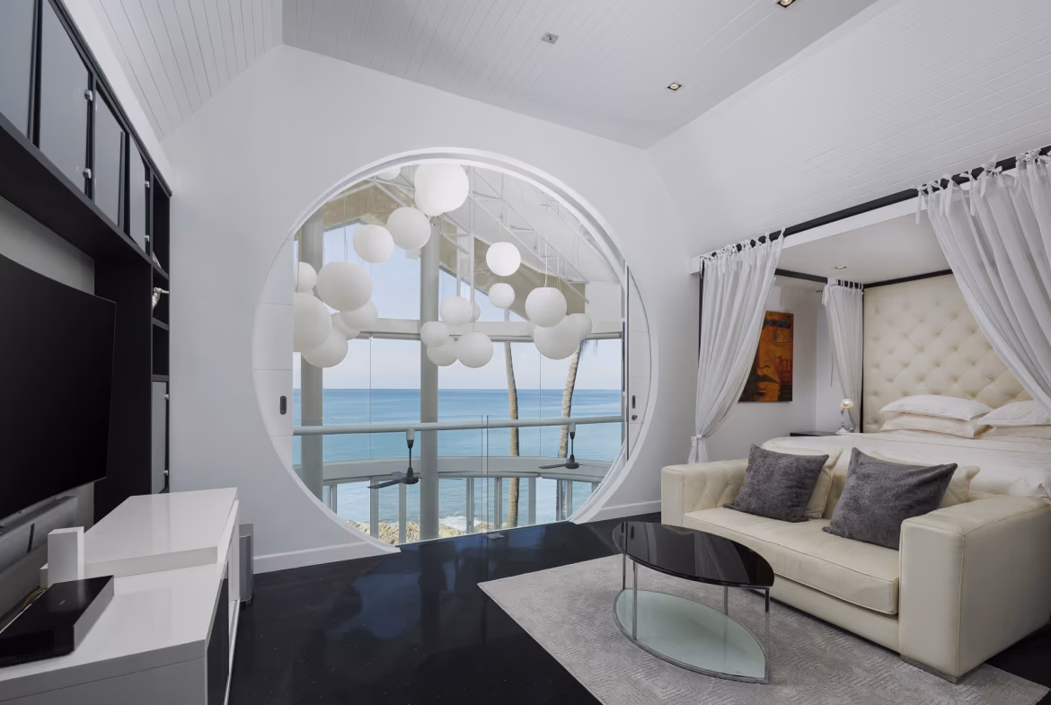 A modern bedroom with minimalist furnishings and a view of the ocean.