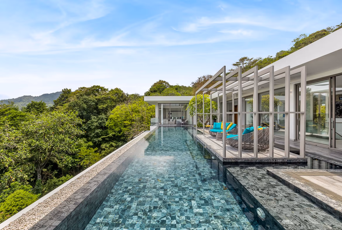 A wide, panoramic view of an ocean sunset from a luxurious balcony or terrace.