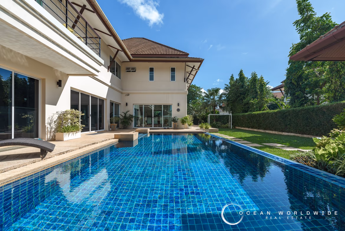 An aerial view of the property shows a large, modern villa with a swimming pool and landscaped gardens.