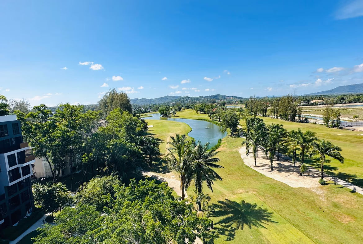 A balcony overlooks a golf course and distant buildings under a clear sky.