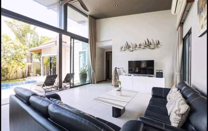 The photo shows an outdoor swimming pool with surrounding lounge chairs and lush tropical landscaping.