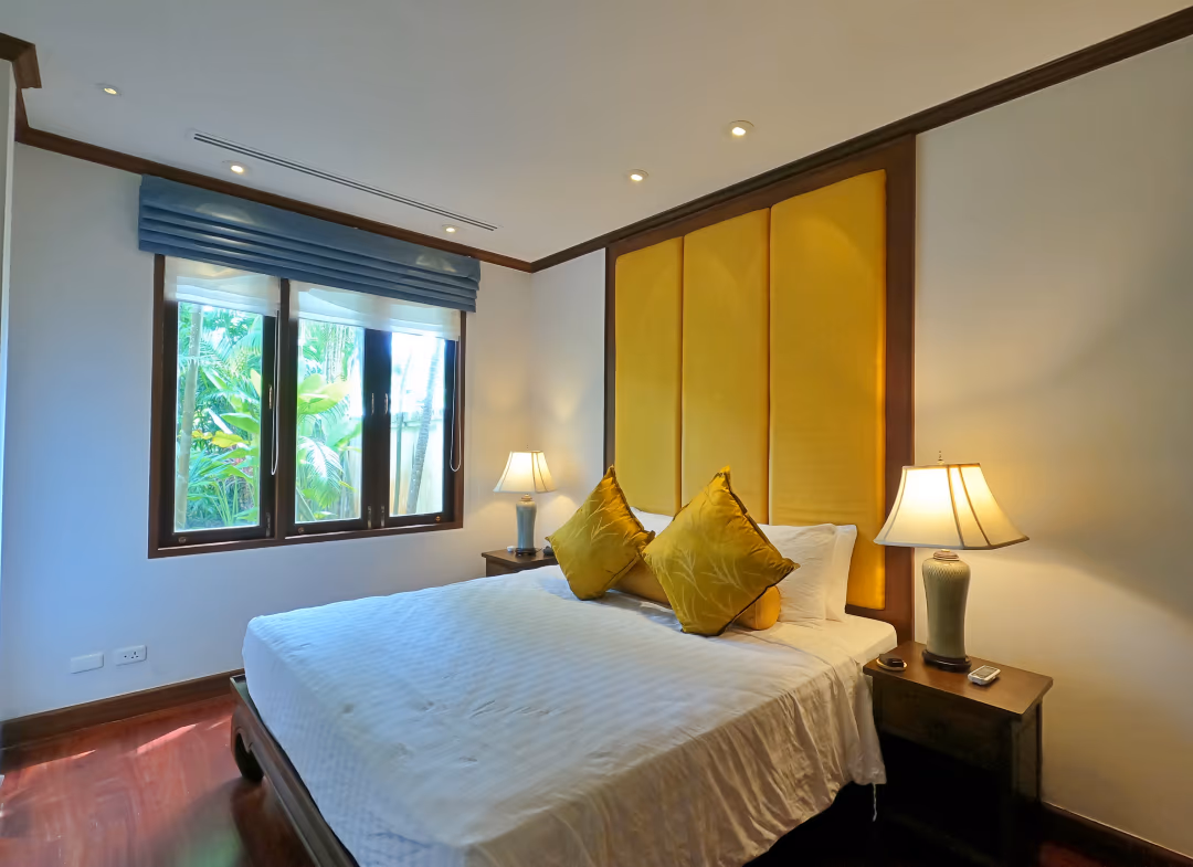 The photo shows a spacious, modern living room with large windows overlooking a lush garden.