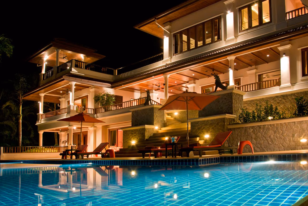 A spacious living area with modern furnishings and large windows overlooks a private swimming pool.