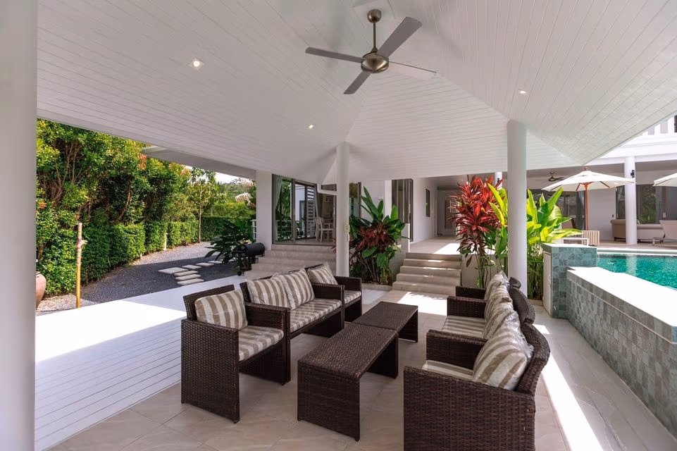 A patio with an outdoor dining table overlooks a swimming pool and a distant lake.