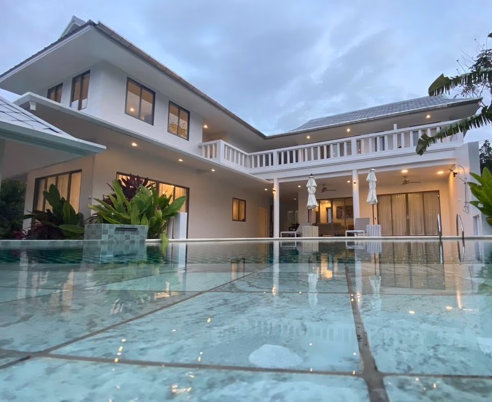 A spacious living room with expansive glass doors offers a view of a lush outdoor area.