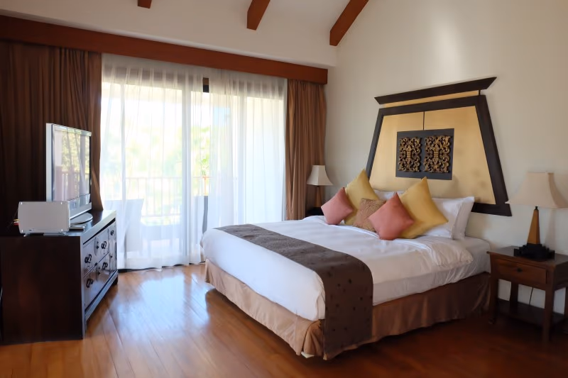 A bedroom with sliding glass doors opening to a private balcony and a view of the lake.