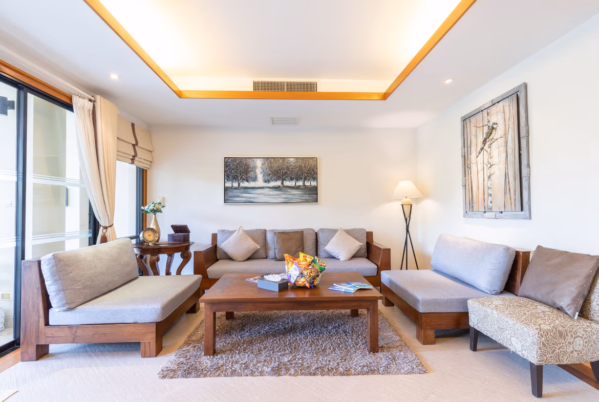 A modern living area with a sofa, a large area rug, and sleek dark furniture, featuring a patio door leading to an outdoor space.
