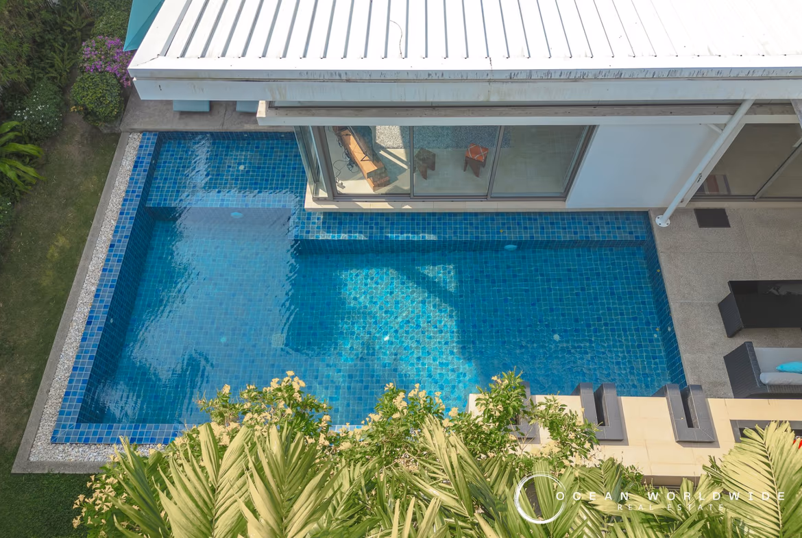 A spacious living area with modern furnishings and large windows overlooks a tropical landscape.