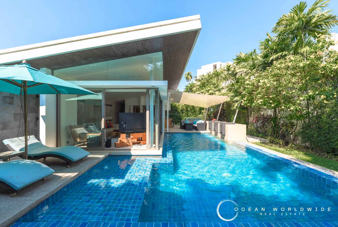 The photo shows a modern bathroom with a freestanding bathtub and a large window overlooking a lush garden.