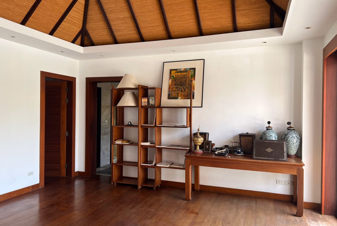 A spacious living room features a vaulted, beamed ceiling and large windows.