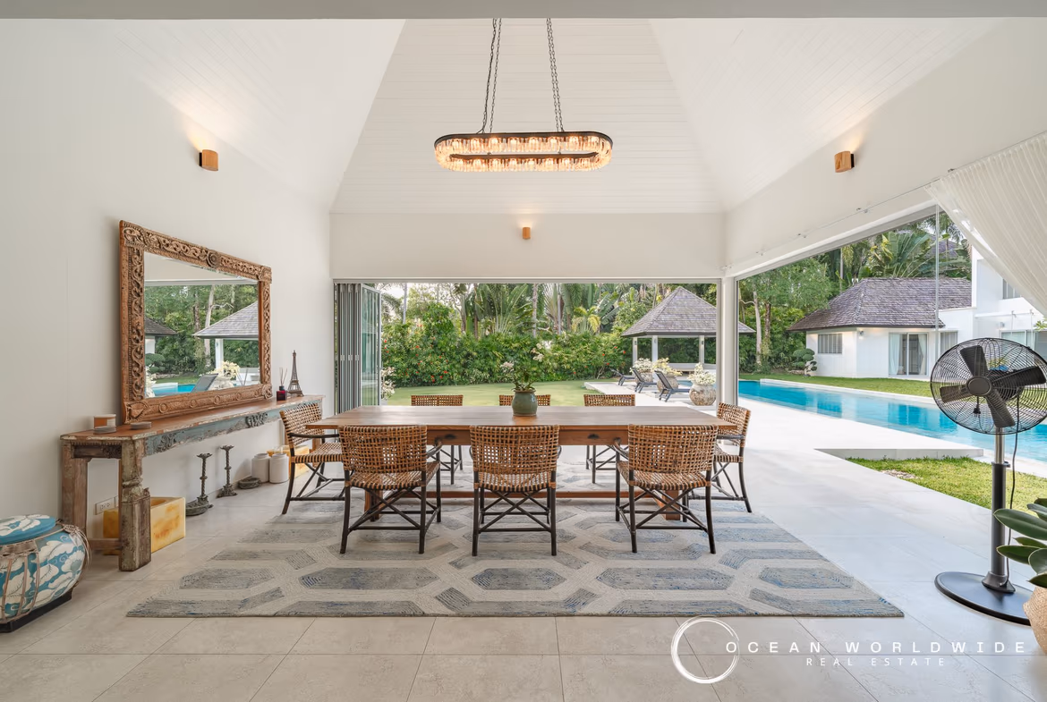 A luxurious bedroom with a king-sized bed, dark wood furniture, and direct access to an outdoor patio with a swimming pool.