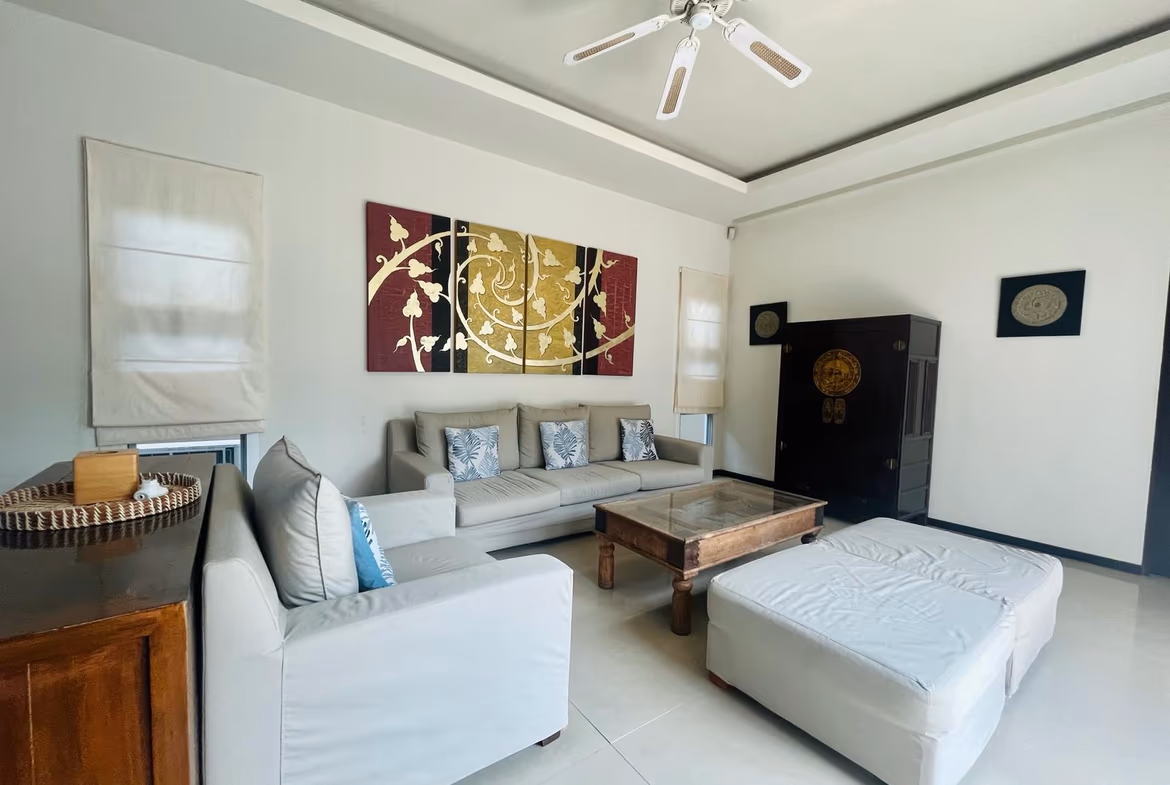A spacious living room with modern furnishings and a large flat-screen TV.