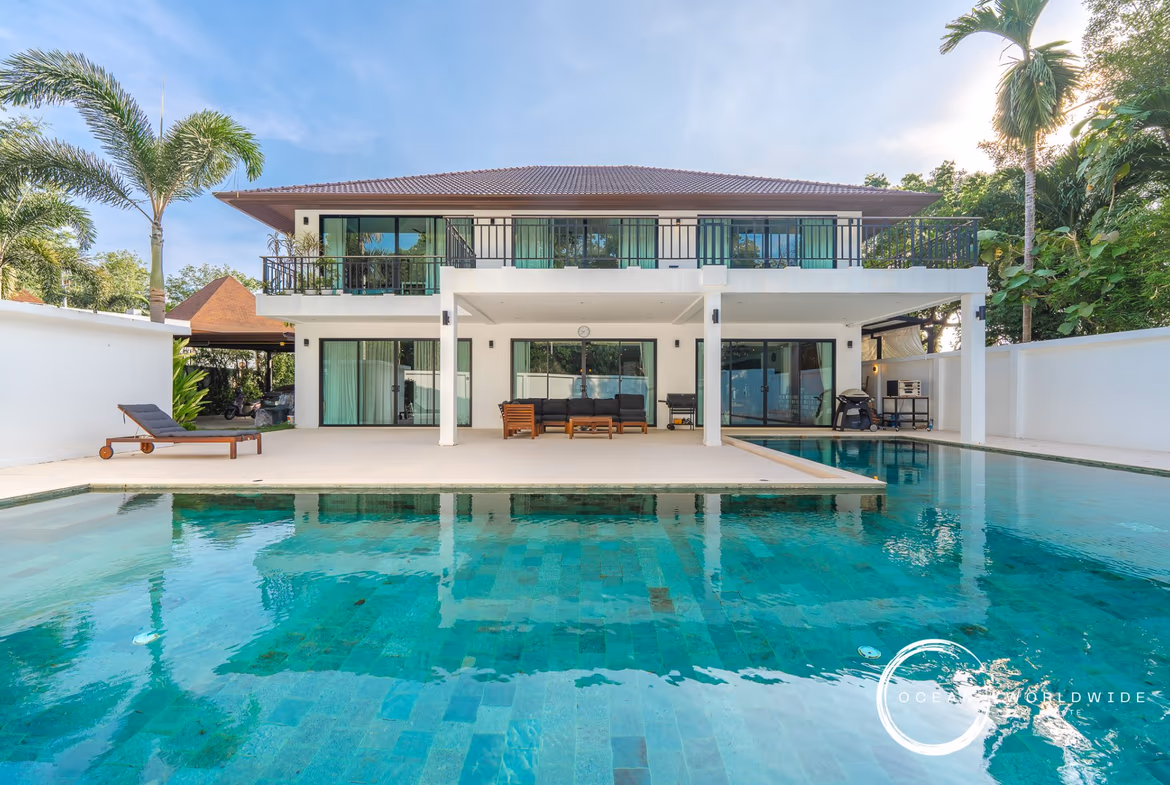 Exterior front shot of a 5-bedroom luxury villa in Cherngtalay. The modern architecture is complemented by a private pool in the foreground.