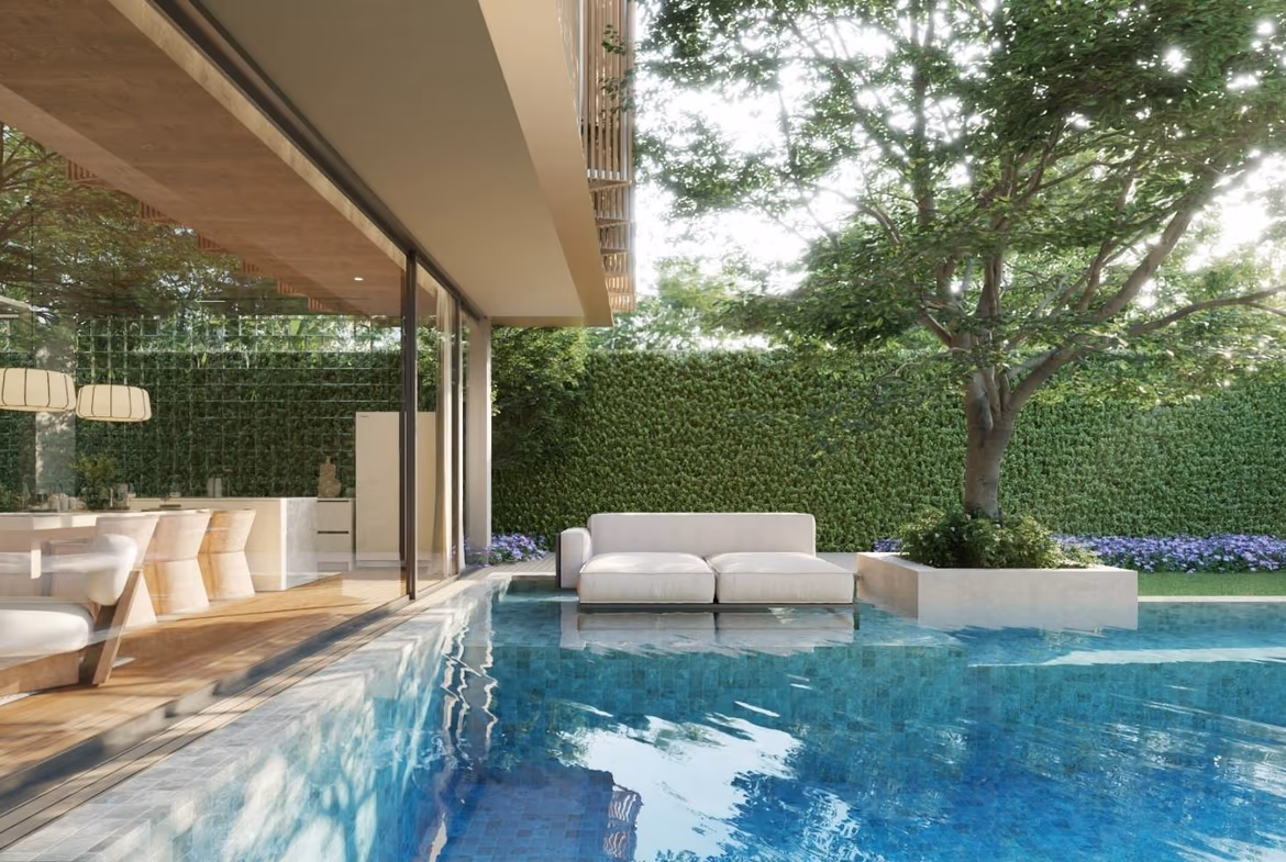 A bright, open-plan living area with an L-shaped sofa and a view of the pool and garden.