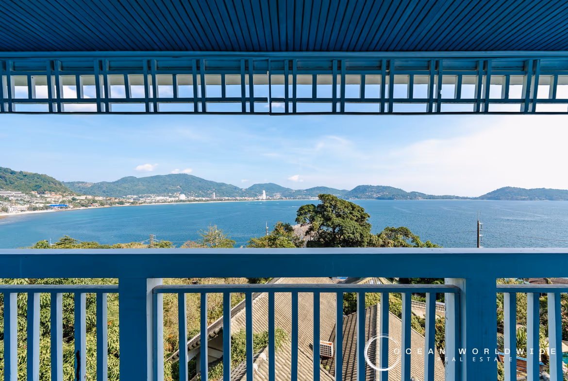 A spacious hotel room with a balcony overlooks the ocean.