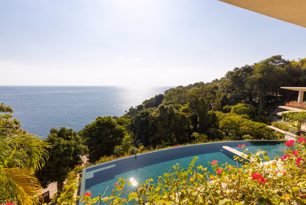 A spacious living area with modern furnishings and large windows showcasing an ocean view.