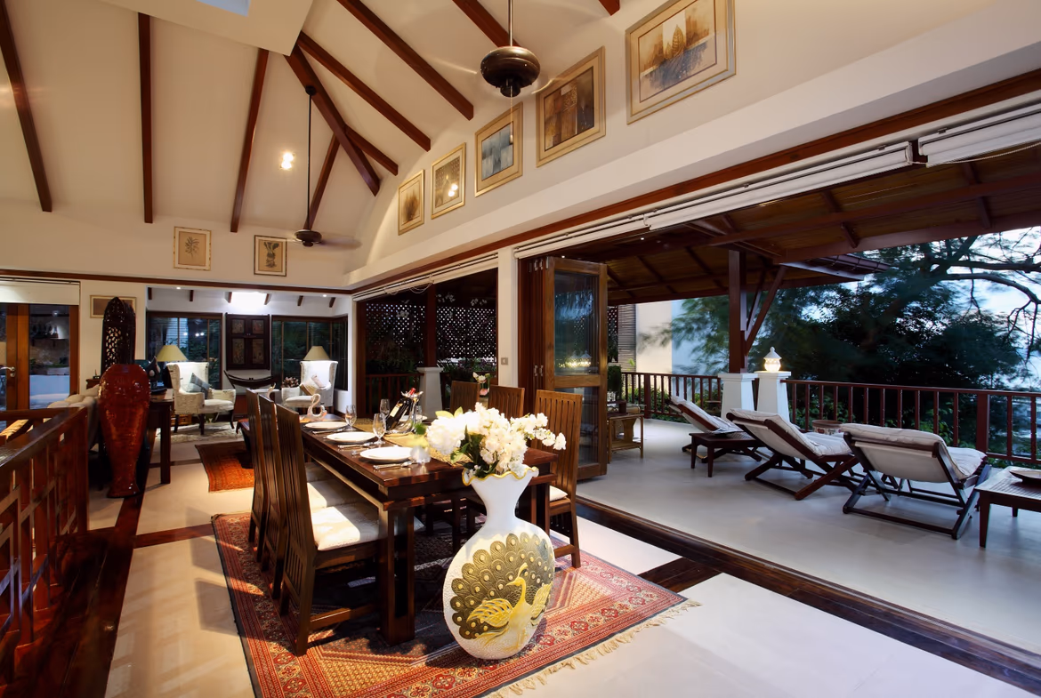 Living room with white sofas and blue accents, facing a sliding glass door with a sea view.