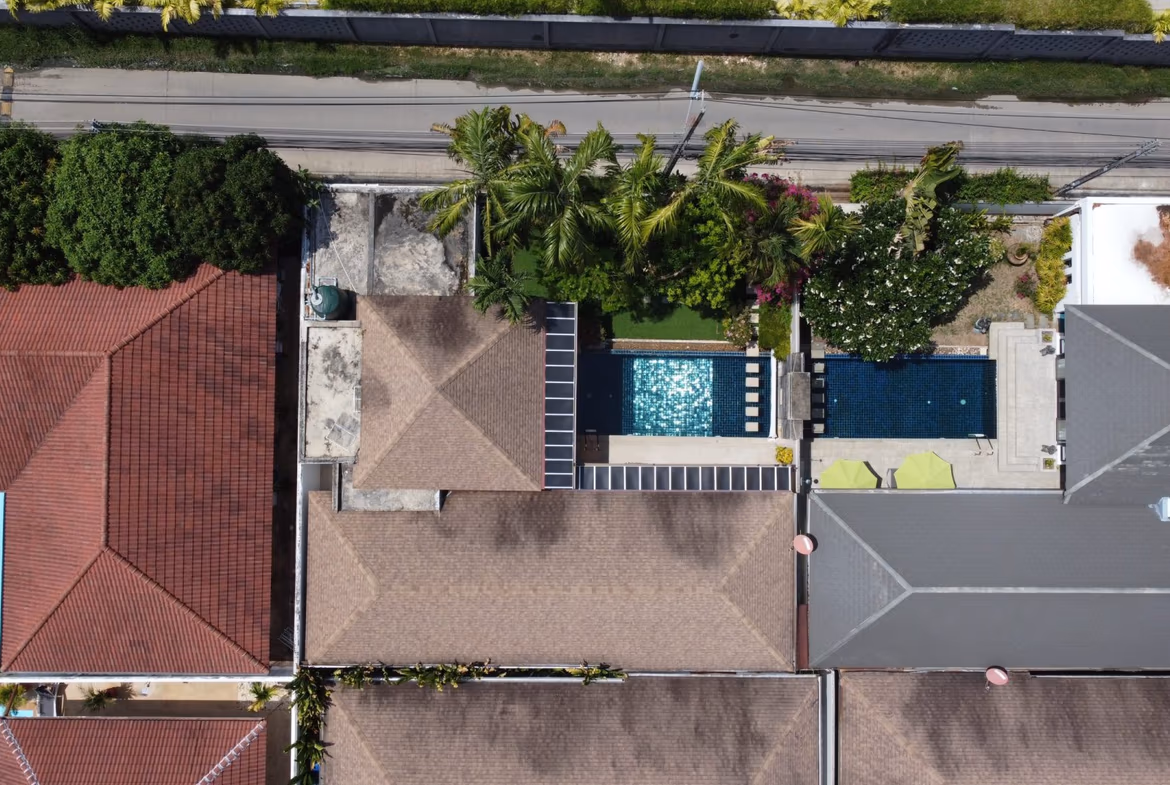 An open-concept living area with a sofa and an adjacent dining table, overlooking a balcony and lush greenery.