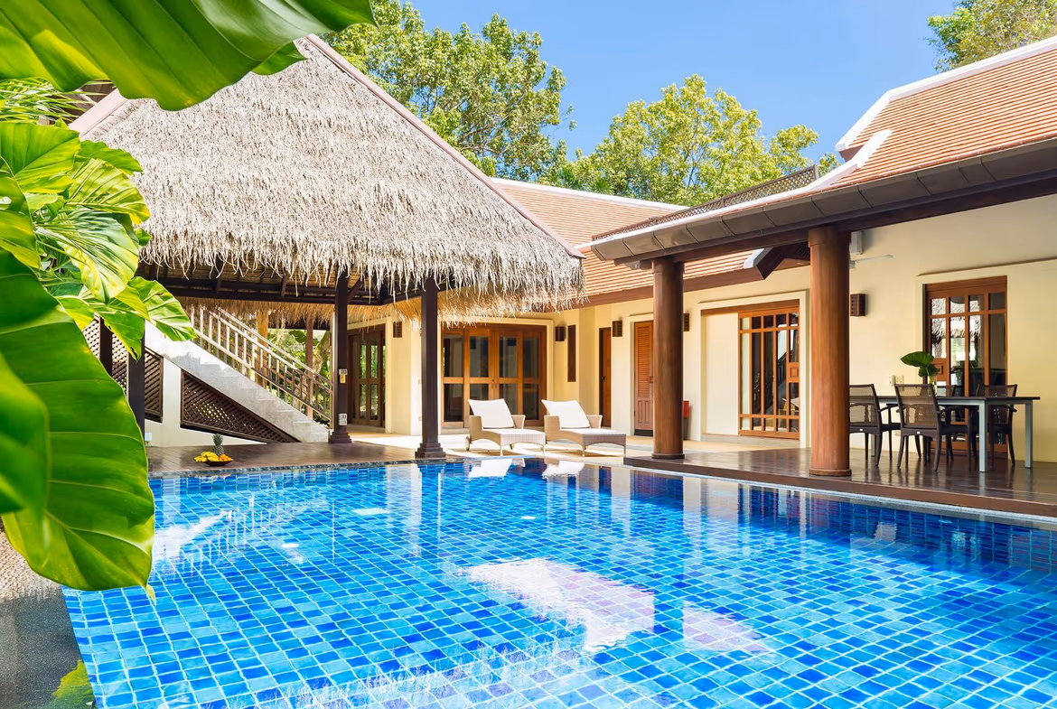 A spacious living area with a large sofa and television opens to an outdoor pool and patio.
