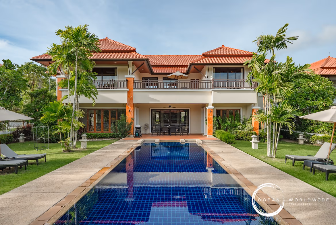 View of a 4-bedroom villa in Laguna with a lake in the background and a private pool in the foreground. The villa features a modern design with large windows and a balcony.