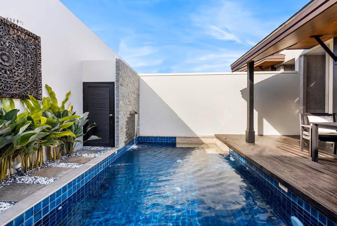 A spacious bedroom features a large bed, wooden floors, and a sliding glass door leading to a patio with a swimming pool.