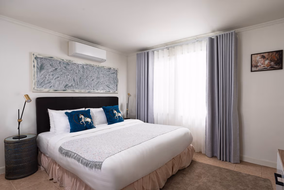 A spacious bedroom with a private balcony overlooking the ocean.