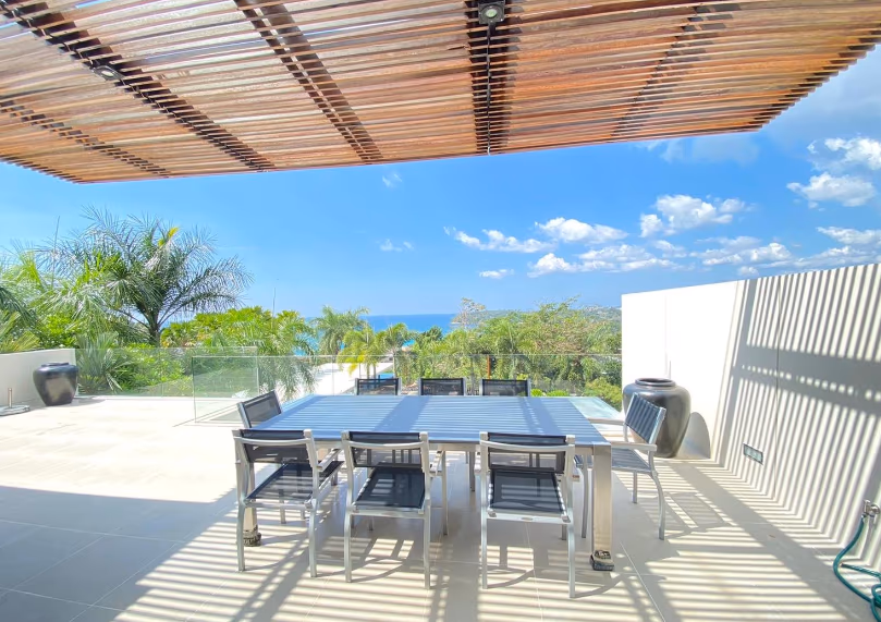 A spacious living room with large windows offering a panoramic view of the sea.
