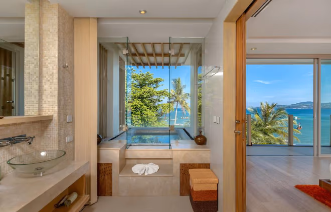 A modern kitchen and dining area with light wood cabinetry and a view of the ocean.