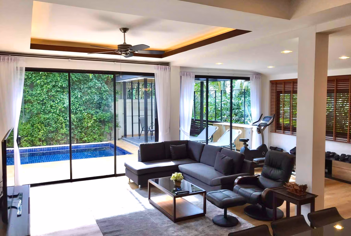 A dining area features a wooden table and chairs, illuminated by natural light from a large window.