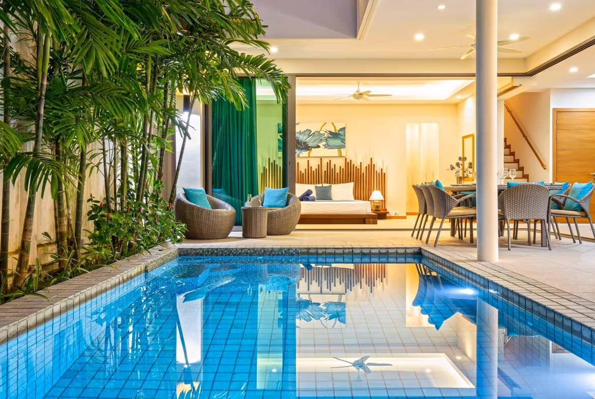 A spacious master bedroom with a large window overlooking the pool and tropical foliage.