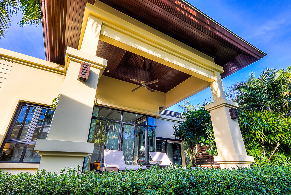 A spacious living room with large windows overlooking a patio and swimming pool.
