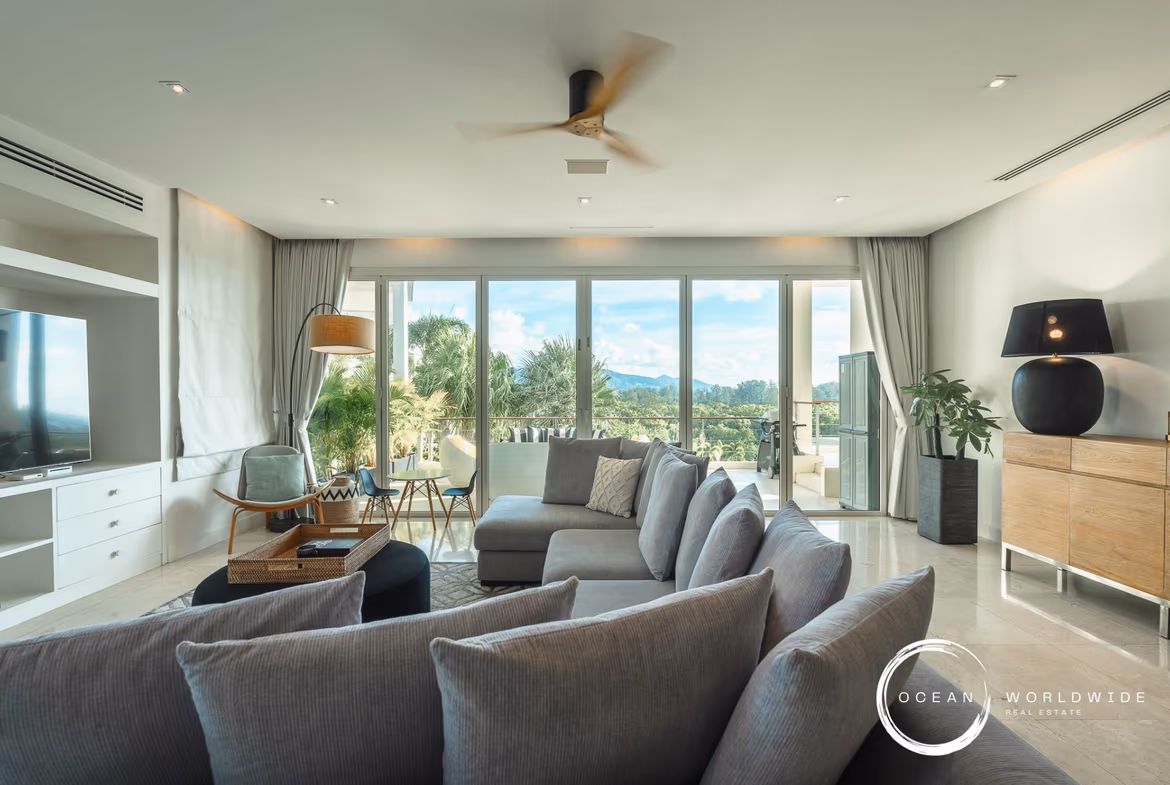 A spacious, modern living room with large windows overlooking the ocean.