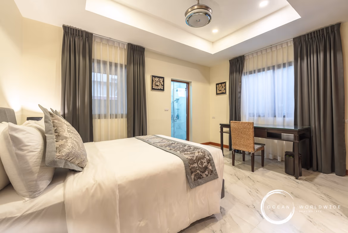 A spacious bedroom with a private balcony overlooking a golf course.