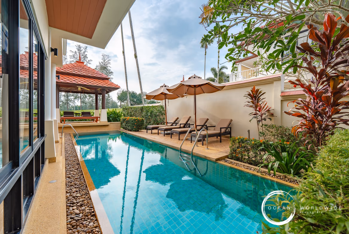 A modern open-plan living area with a sofa, dining table, and kitchen in a golf course view villa.