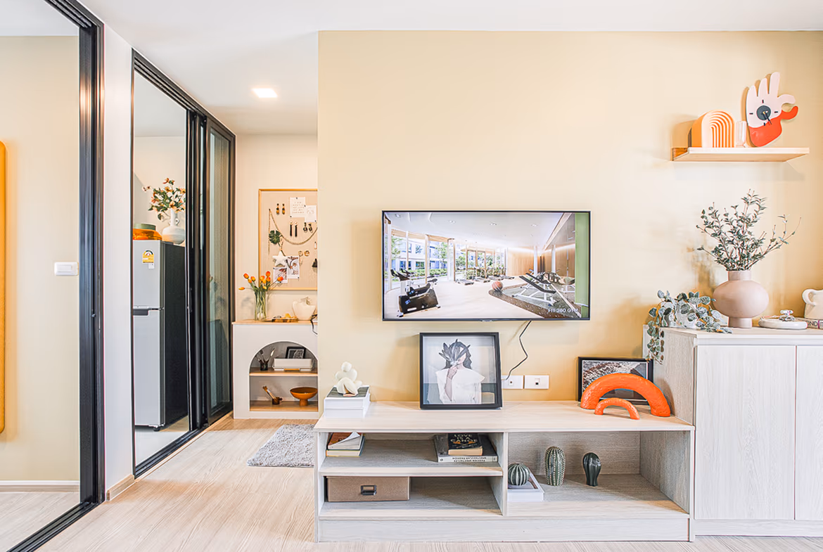 A modern living room with a large sofa and television opens to a balcony with mountain views.