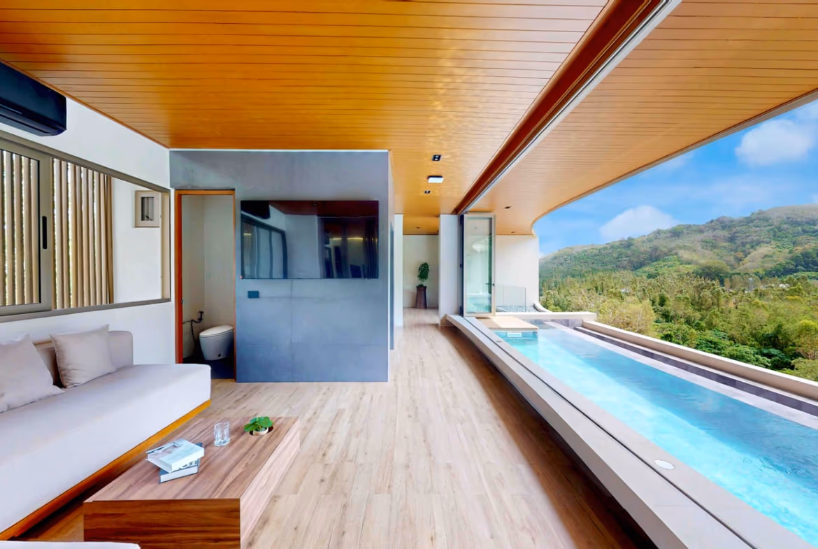 A bright living space features a large sectional sofa, a flat-screen TV, and sliding glass doors that open to an outdoor area.