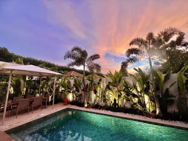 Modern 3-bedroom villa in Phuket featuring a private pool and manicured landscaping. The property has white exterior walls and large windows, surrounded by lush tropical vegetation.