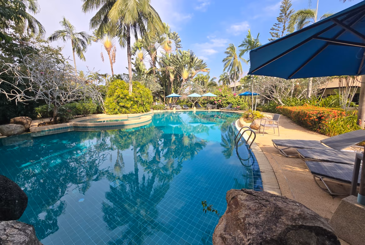 A three-bedroom villa in Bang Tao, located near the beach. The home has a red tile roof and a fenced yard.