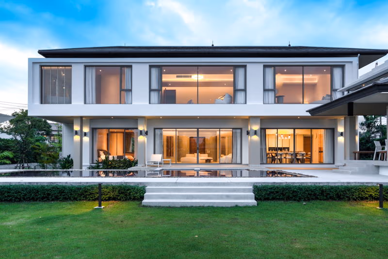 A modern 5-bedroom villa in Phuket featuring a private pool. The spacious residence has large glass doors that open to the outdoor patio and pool area.